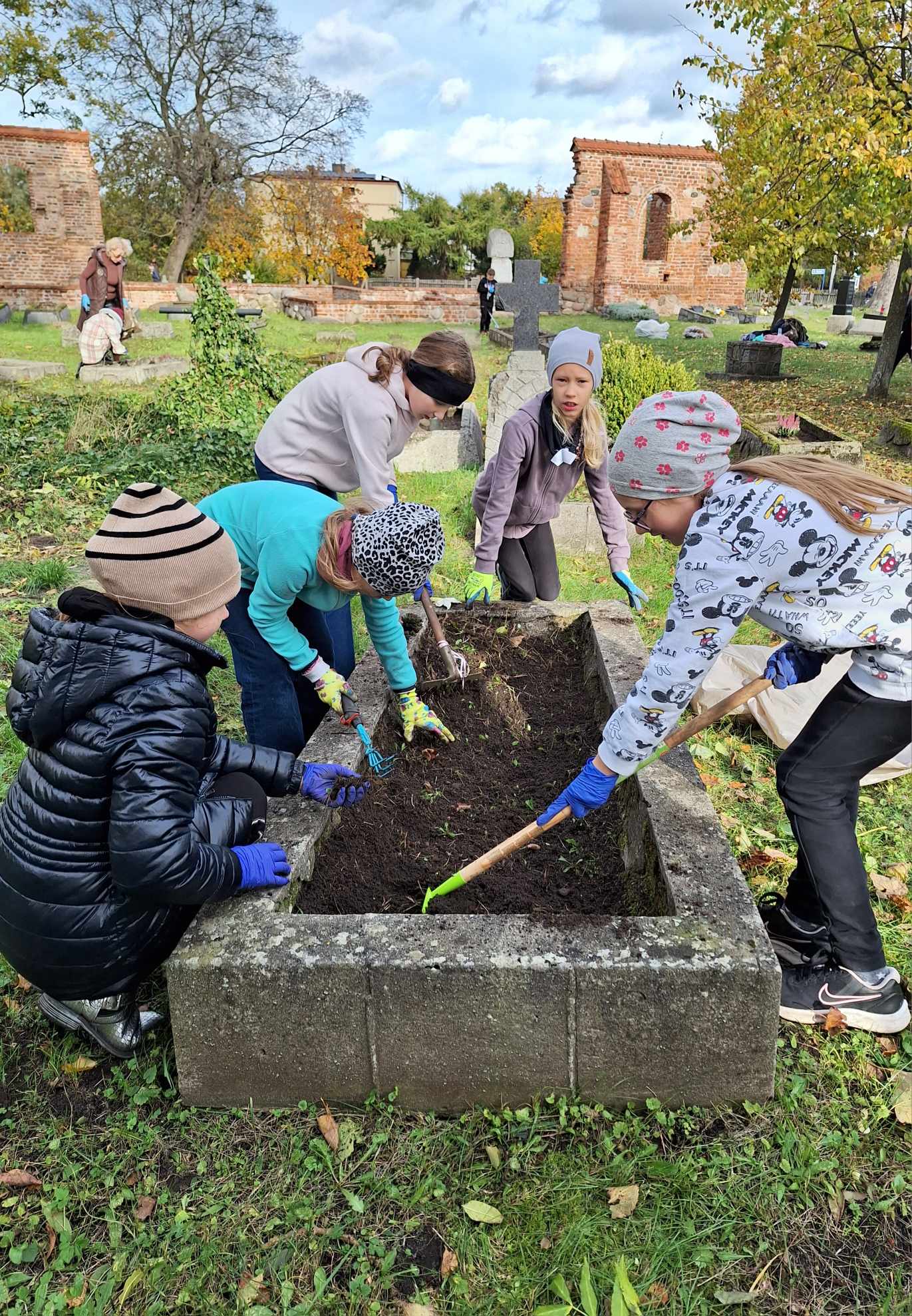 Uczniowie przy jednej z zabytkowych mogił, które znajdują się na historycznym cmentarzu, fot. Monika Jastrzębska / SP nr 1 w Rumi