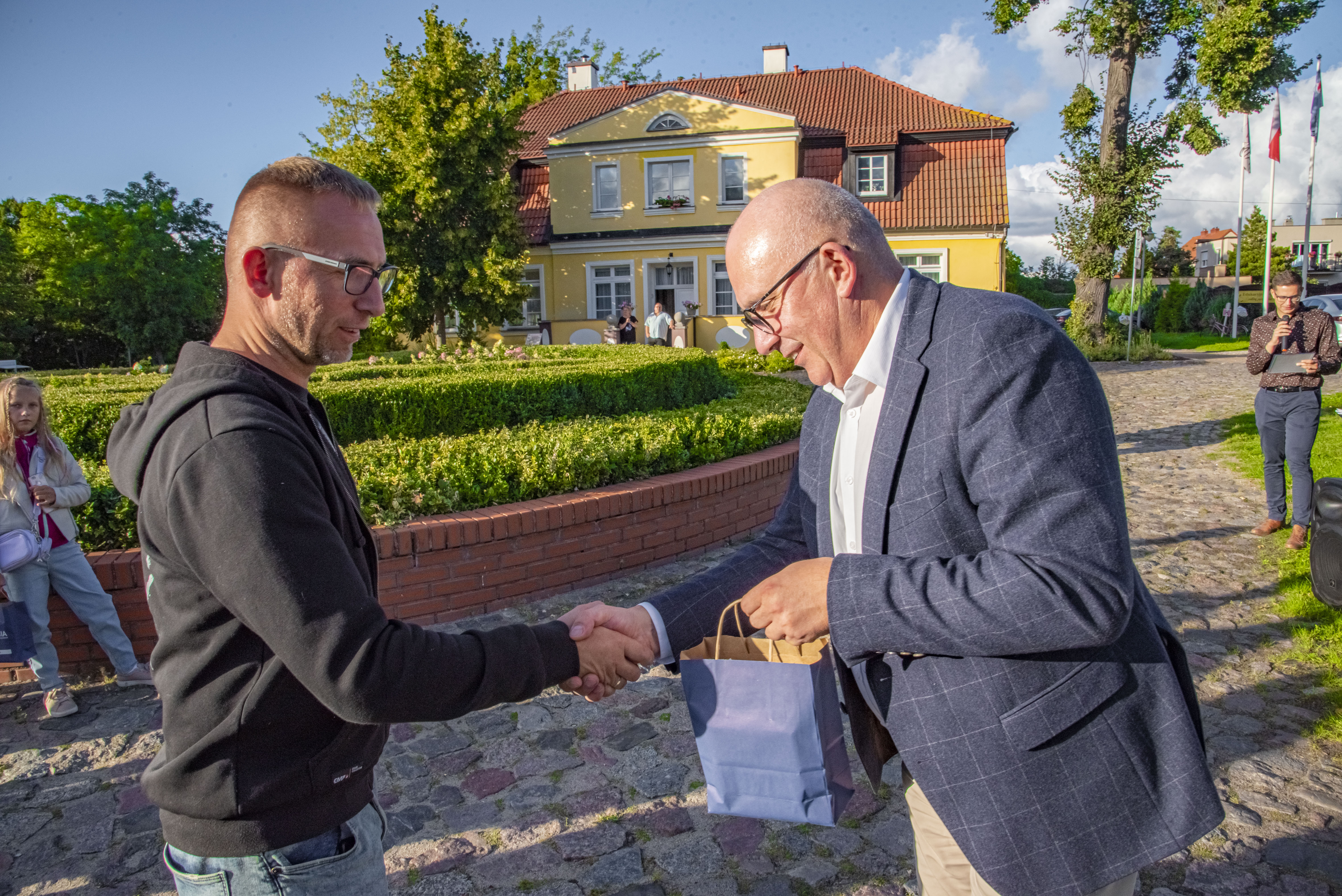 Piotr Wittbrodt (wówczas wiceburmistrz Rumi) gratulujący Danielowi Pietrzykowskiemu udziału w wystawie grupy „Z aparatem po Rumi” (wrzesień 2022 r.)