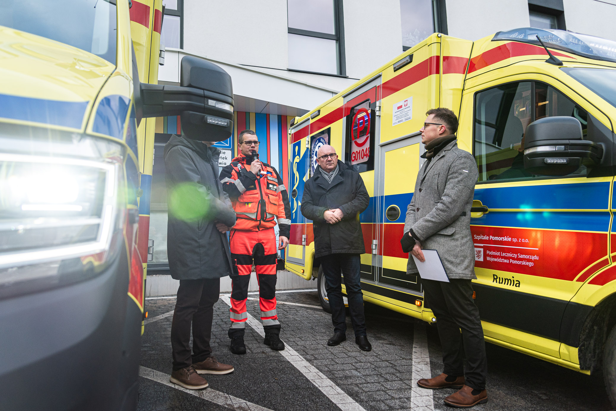 Przekazanie nowych ambulansów, przemawia Marek Kukuczka, obok, po prawej, pełnomocnik burmistrza ds. społecznych Piotr Wittbrodt